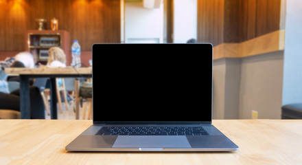 Naklejka premium black screen laptop on wood table in cafe light