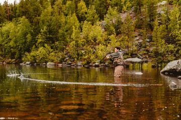 Fototapeta na wymiar Fisherman using rod fly fishing in mountain river autumn splashing water