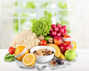 Raw oats in bowl and fruit salad, apples on the wooden table