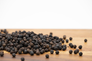 Dry heap black pepper isolated on wooden chopper board with copy space text