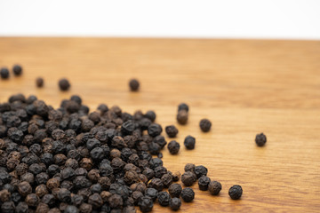 Dry heap black pepper isolated on wooden chopper board with copy space text