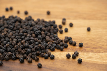 Dry heap black pepper isolated on wooden chopper board