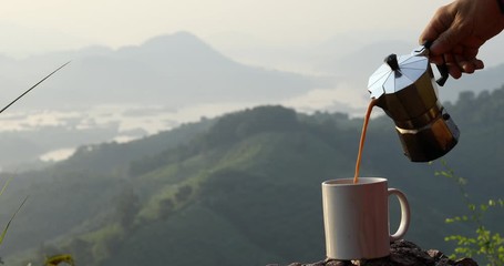 Hands pouring coffee from Moka pot in the morning on the beautiful hilltop,moka pot coffee maker,Coffee and nature
