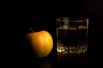 glass of apple juice and an apple isolated on black background