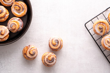 Homemade baked cinnamon rolls baked in an iron skillet cooling on cooling rack with icing