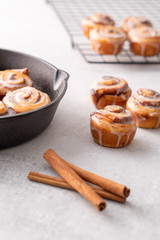 Homemade baked cinnamon rolls baked in an iron skillet cooling on cooling rack with icing