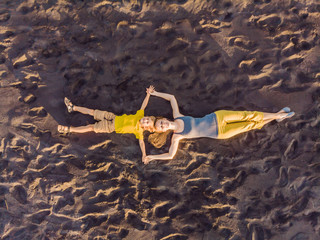 Mom and son are lying on the sand at sunset. View from the drone. Paradise, travel, vacation concept