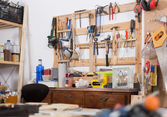 Old tools hanging on wall in workshop, tool shelf against a wall