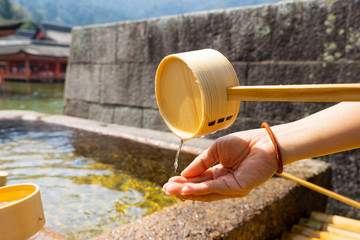 People clean their hand by pouring water at shrine in Japan.