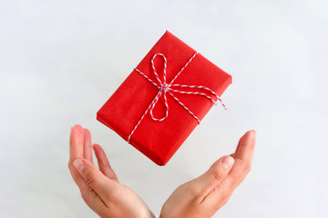 handmade red gift box fly into female hands on a white background