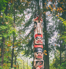 Alaska totem pole carving art sculture tourist travel destination forest background. Ketchikan,...