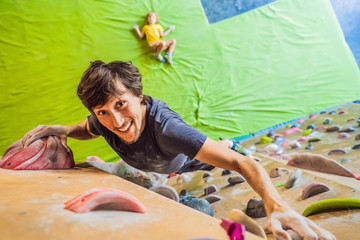Muscular man practicing rock-climbing on a rock wall indoors