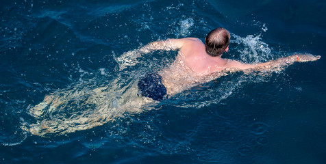 A girl swims in the blue water of the sea