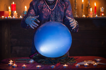 Hands of fortune teller with illuminated crystal ball