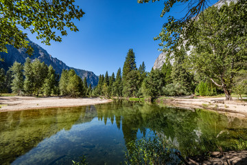 Fototapeta na wymiar Branches hang from the top in the foreground of Merced River looking towards half dome in Yosemite National Park