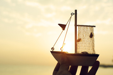 Hand holding model boat and the sea background.