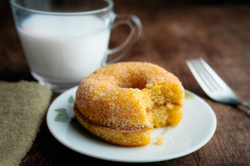 Tasty  fluffy yeast doughnuts or sugared donut  on white  plate and glass of milk on wood table, Best Morning recipe. 