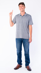 Full body shot of happy young handsome man pointing up