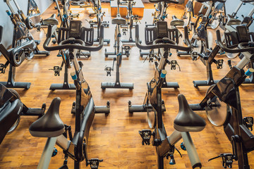 Aerobics spinning exercise bikes gym room with many in a row