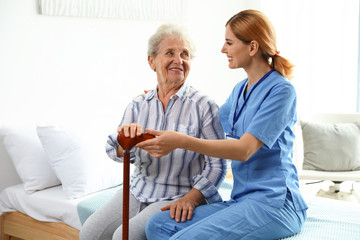 Obraz premium Nurse in uniform assisting elderly woman indoors