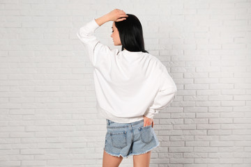 Young woman in sweater at brick wall. Mock up for design