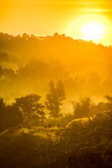 Foggy early morning in the mountains with shadows and silhouettes of forest and hills.