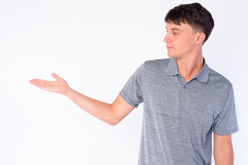 Portrait of young handsome man looking to the side and showing something