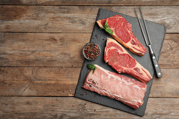 Fresh meat on wooden table, flat lay. Space for text