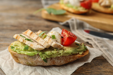 Delicious chicken bruschetta on wooden table, closeup