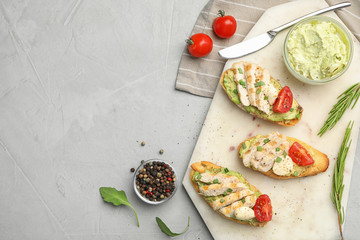 Board with delicious chicken bruschettas on light grey table, flat lay. Space for text