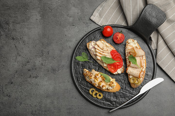 Slate plate of delicious chicken bruschettas on dark table, top view. Space for text