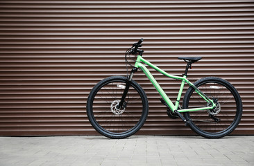 Obraz na płótnie Canvas New modern color bicycle near brown wall outdoors