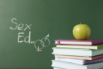 Books and apple near chalkboard with phrase 