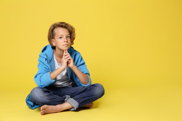 Fototapeta na wymiar Cute little boy in casual outfit on yellow background. Space for text