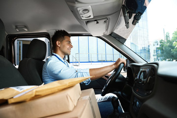 Naklejka premium Young courier with parcels in delivery car