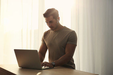 Portrait of young man with laptop at table indoors