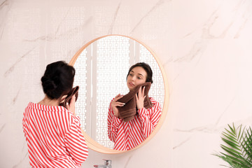 Young woman with towel near mirror in bathroom