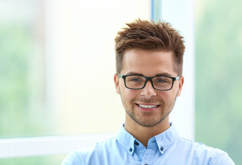 Obraz premium Portrait of handsome young man with glasses near window