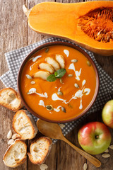 Pumpkin apple puree soup with seeds, yogurt and mint closeup. Vertical top view