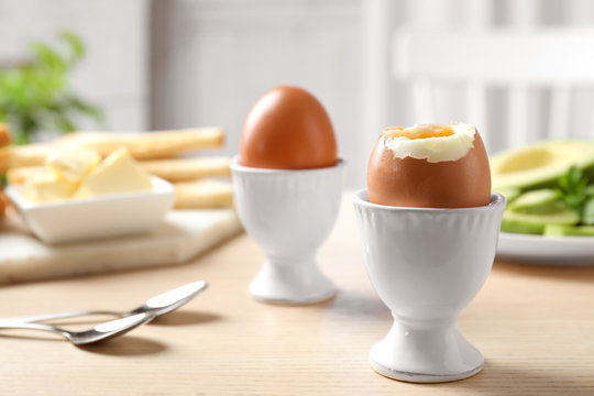 Cups with soft boiled eggs on wooden table, space for text. Healthy breakfast