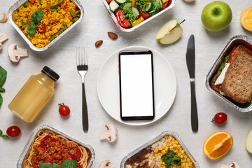 Flat lay composition with lunchboxes and smartphone on white wooden table, mockup for design. Healthy food delivery
