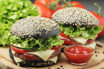 Two black burgers with vegetables and beef meat