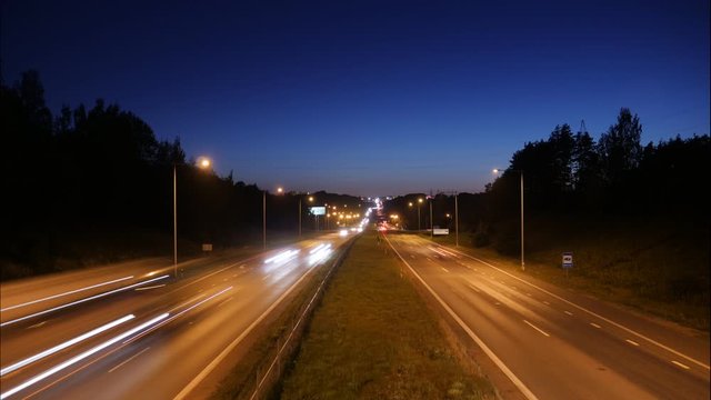 Static timelapse of cars driving on a motorway at twilight with the sky darkening