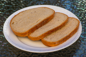 Slices of simple wheat bread on white plate, ready to eat, food and drink