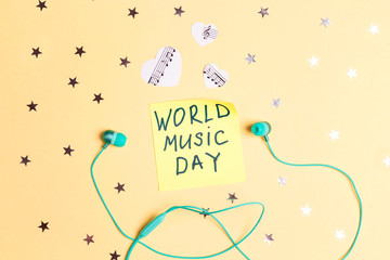 International Music Day background with turquoise earphones and music hearts on  yellow background. Top view, flat lay.