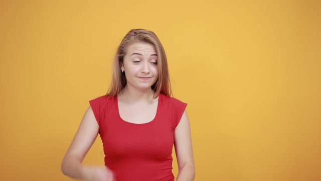 young blonde girl in red t-shirt over isolated orange background shows emotions