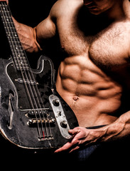 Instrument on stage and band. Strong, muscular, muscles man, bodybuilding. Music concept. Electric...