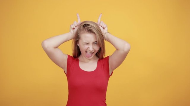 young blonde girl in red t-shirt over isolated orange background shows emotions