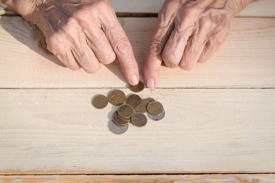 Hands of an elderly man holding coins. The concept of lack of money, the poor, the small pension of old people. Image.