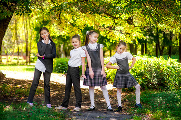 Obraz premium Schoolchildren have fun in the park. Four girls in school uniform are jumping and laughing
